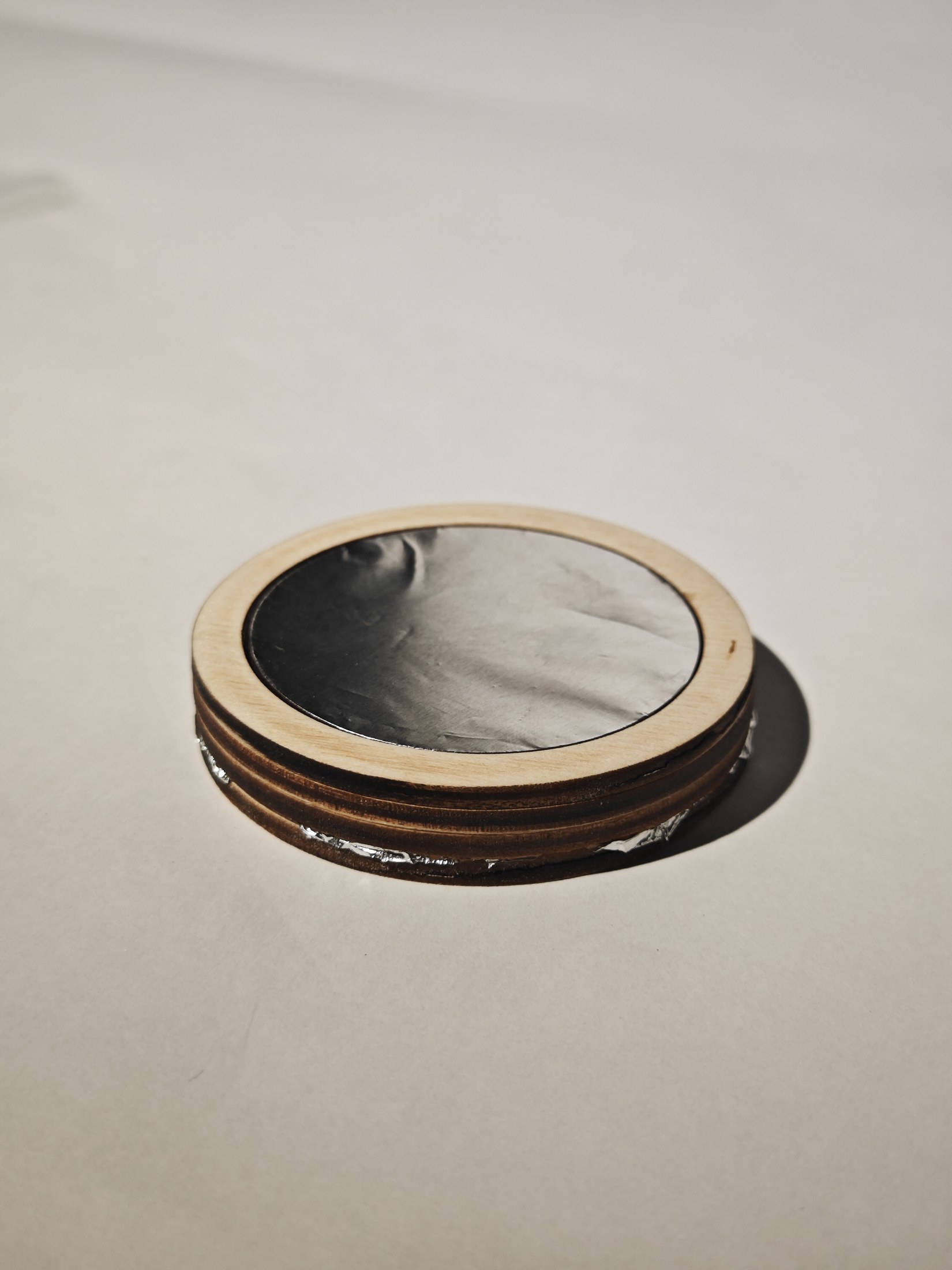 Assembled plywood coaster with an aluminum foil sensing surface