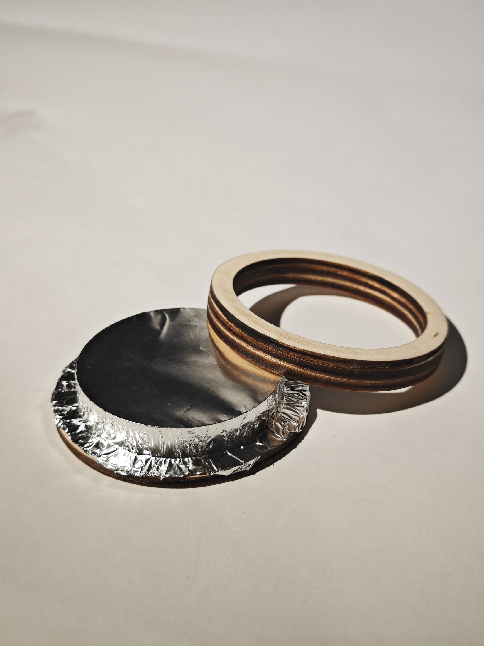 Plywood coaster opened to reveal its aluminum foil layer