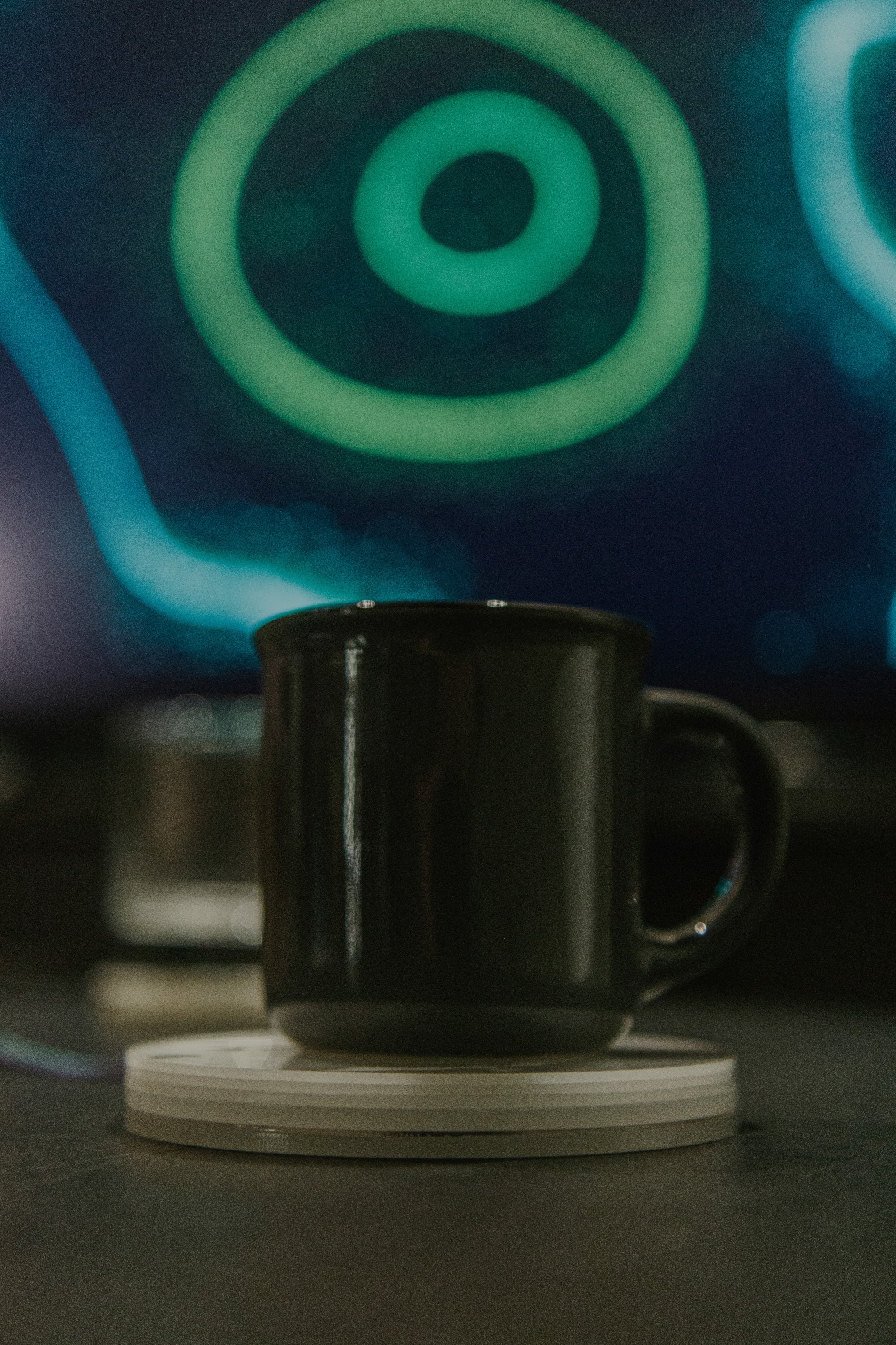Black mug resting on a finished white sensor coaster in front of the projection